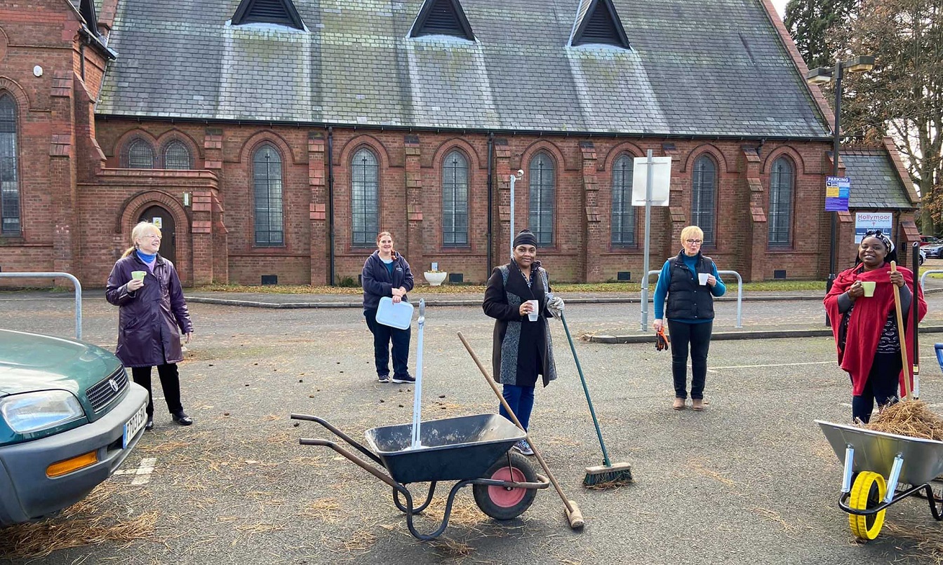Group of volunteers with brooms and wheelbarrows